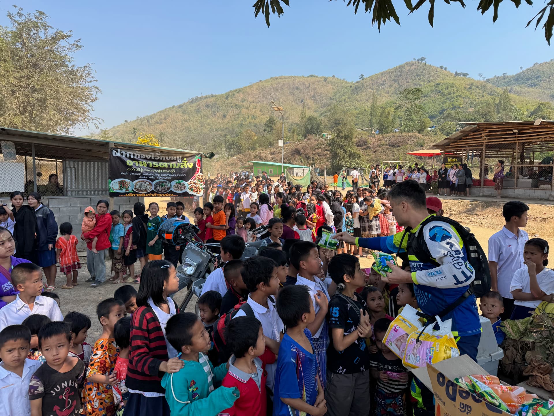 Coleg KUPELO oferind produse copiilor dintr-o tabără de refugiați la granița dintre Myanmar și Thailanda