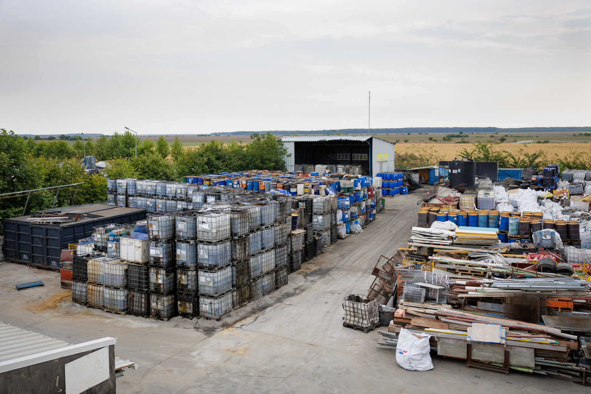 Storage yard with stacked IBC containers, drums and sorted scrap at a KUPELO site